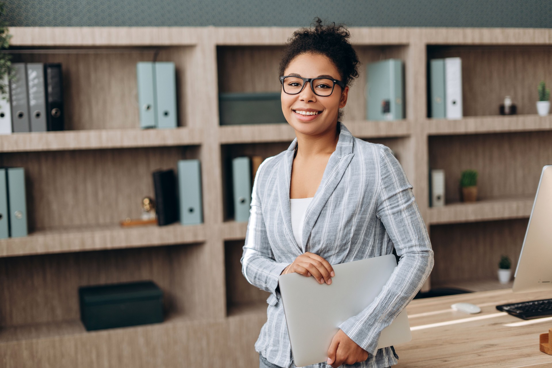 Smiling businesswoman holding laptop in modern office